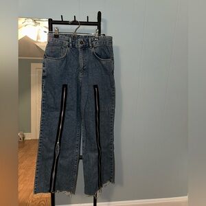 The Ragged Priest Denim Pants with zippers down the front of the pant legs.